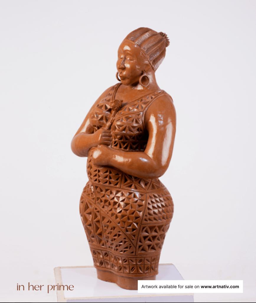 African Art Sculpture named "In Her Prime", is a celebration of feminine beauty and strength. The elegant figure of a woman is depicted holding a flower, symbolizing the grace and elegance of womanhood. Suitable for home décor, interior styling, gifting, personal expression, milestone moments, office spaces, cultural appreciation, and building lasting art collections.
