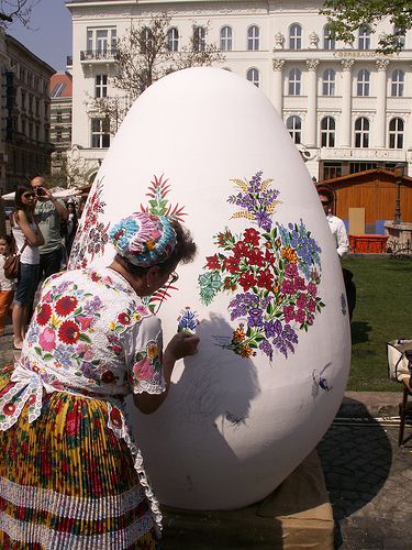 Ukrainian Easter celebration featuring women in traditional embroidered vyshyvanka folk costumes and handmade floral vinok crown wreaths dancing at an outdoor village festival beside a woven basket of vibrant hand-painted pysanky Easter eggs surrounded by fresh spring flowers — how Ukraine celebrates Easter with folk art, cultural traditions, and community gatherings