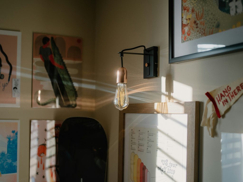 Artwork displayed on a wall beside a warm lamp in a home interior