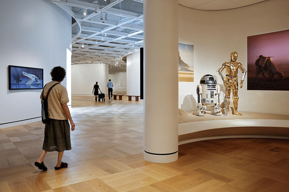 Interior gallery at the Lucas Museum of Narrative Art, with visitors viewing paintings, sculptures, and other artworks.