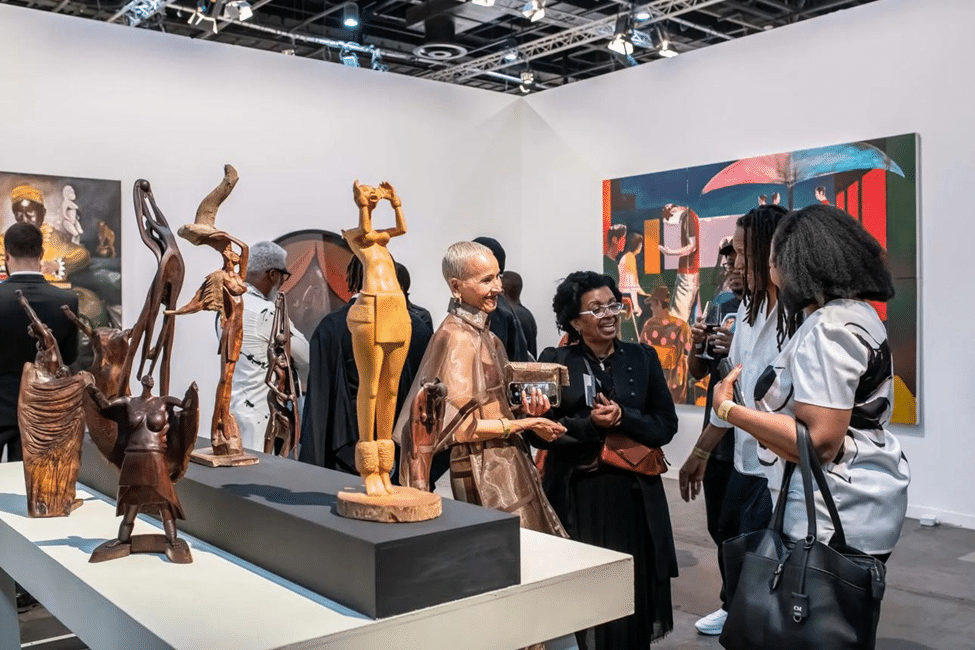 Visitors viewing contemporary African artworks and sculptures at an art fair.