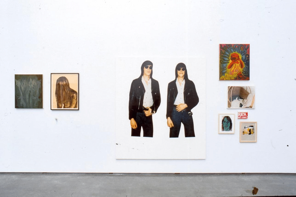 Artwork depicting two women dressed in black standing against a white background in a gallery.